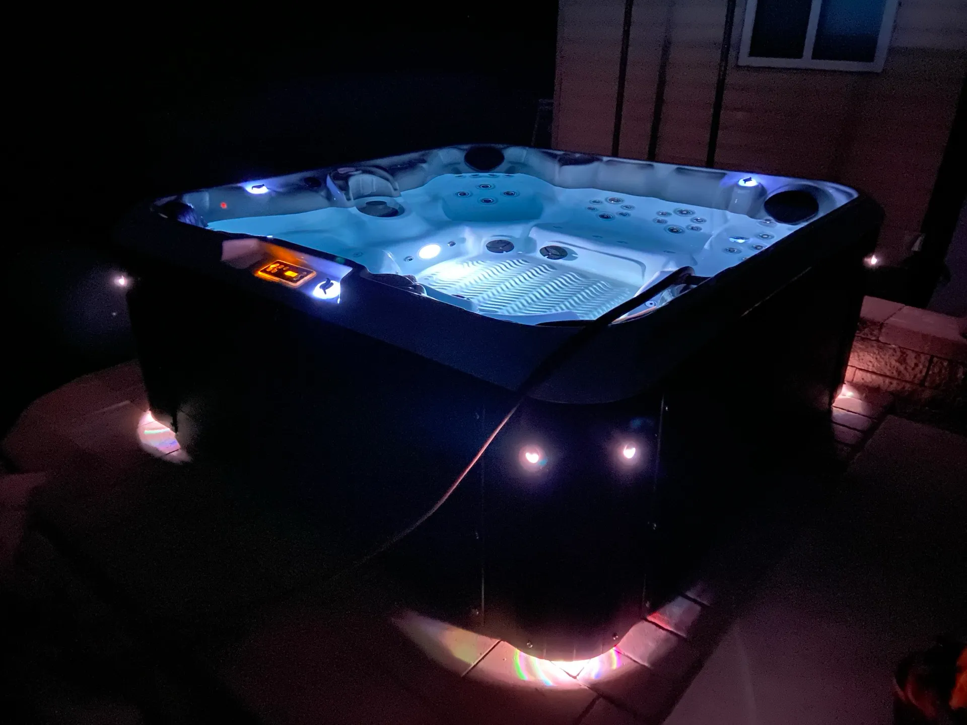 Private hot tub glowing on the back patio at night