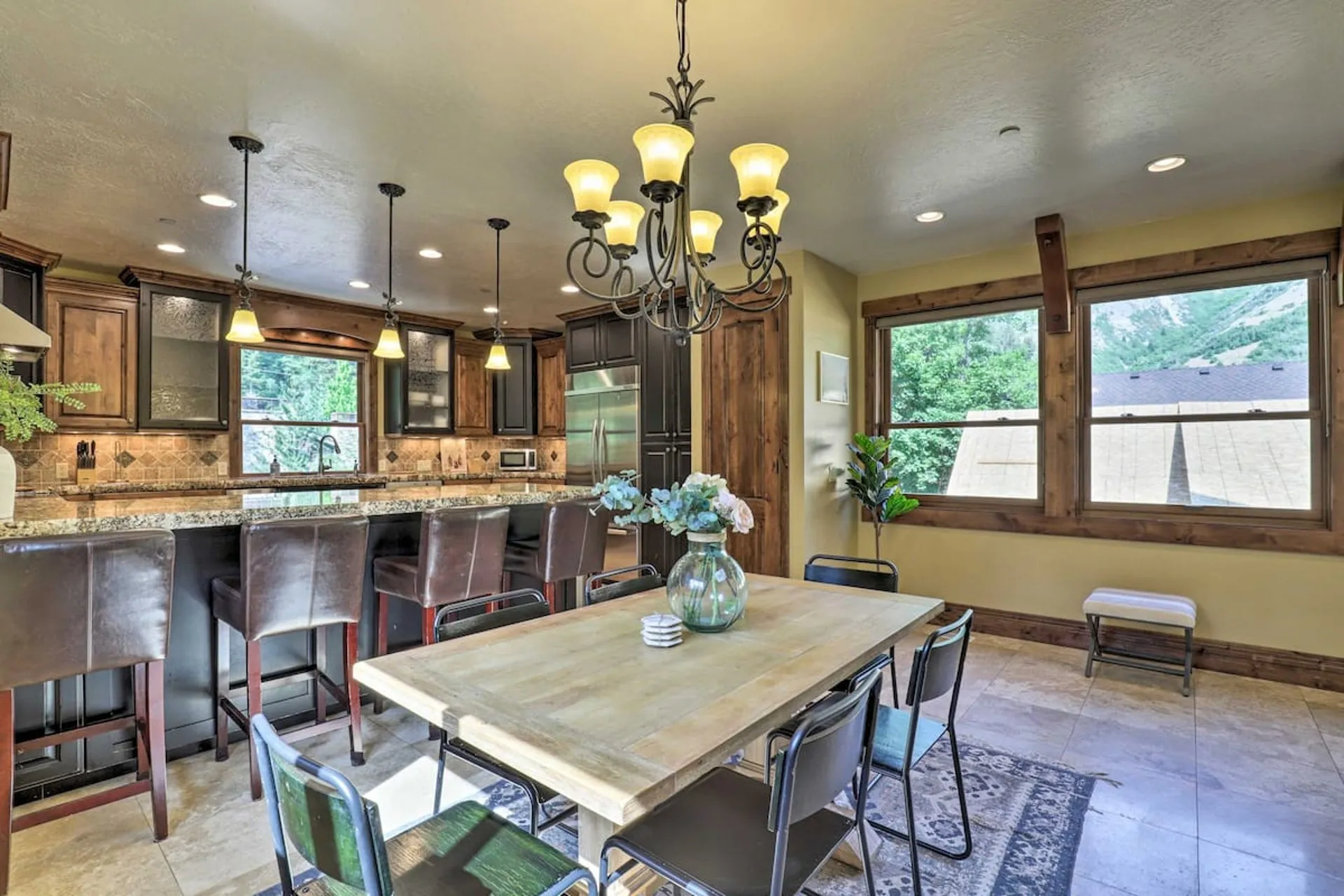 Full kitchen with granite island and dining table seating six under a wrought-iron chandelier